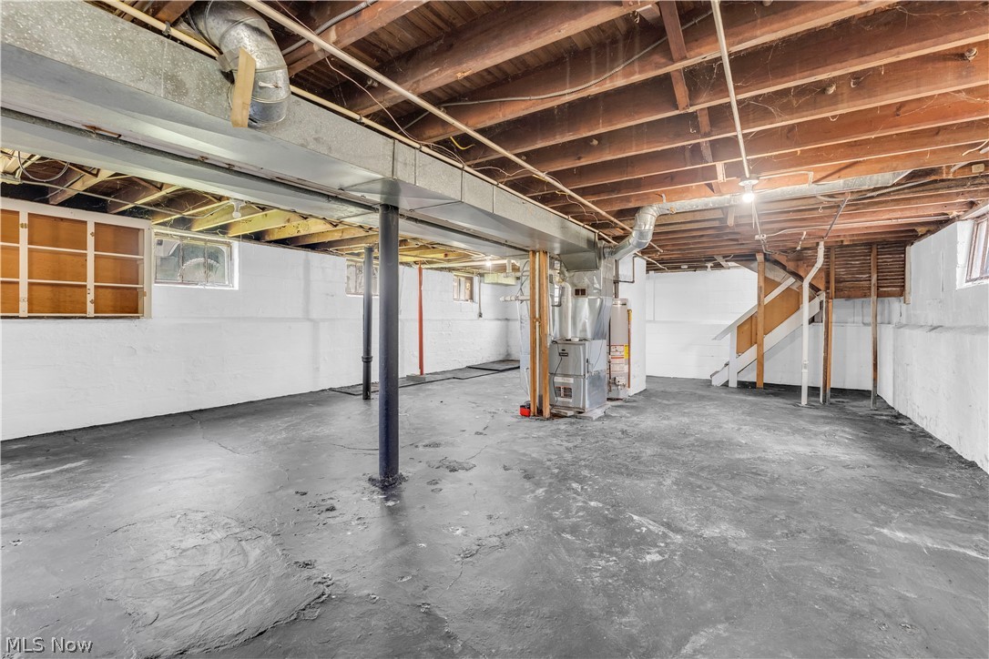 18123 McCracken Road Maple Heights, OH 44137 - Photo 25 of 27 Expansive unfinished basement featuring concrete flooring, exposed wood joists, white-painted foundation walls, support columns, and visible utility infrastructure including ductwork and furnace