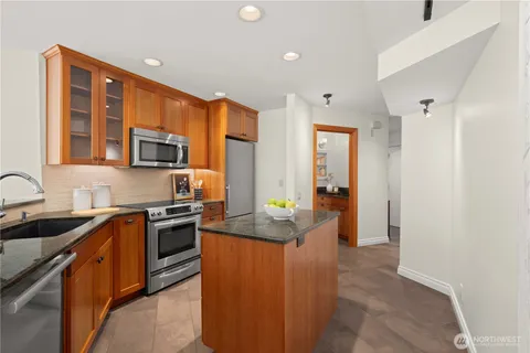 a kitchen with stainless steel appliances granite countertop a sink stove refrigerator and cabinets