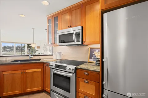 a kitchen with stainless steel appliances granite countertop a stove a sink and a microwave