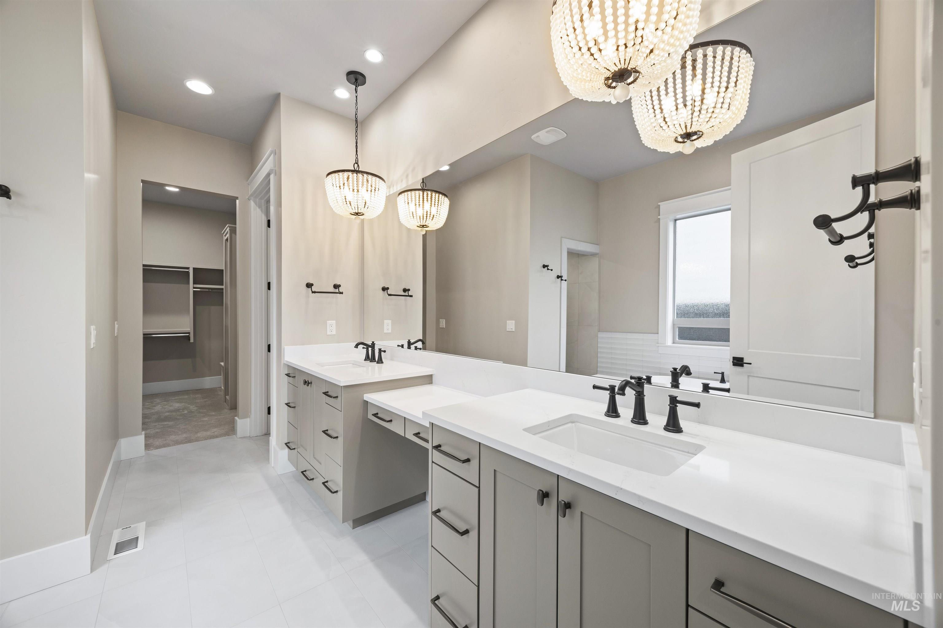 934 East Escalation Street Meridian, ID 83642 - Photo 11 of 50 Full bath with a chandelier, two vanities, a walk in closet, and light tile patterned floors