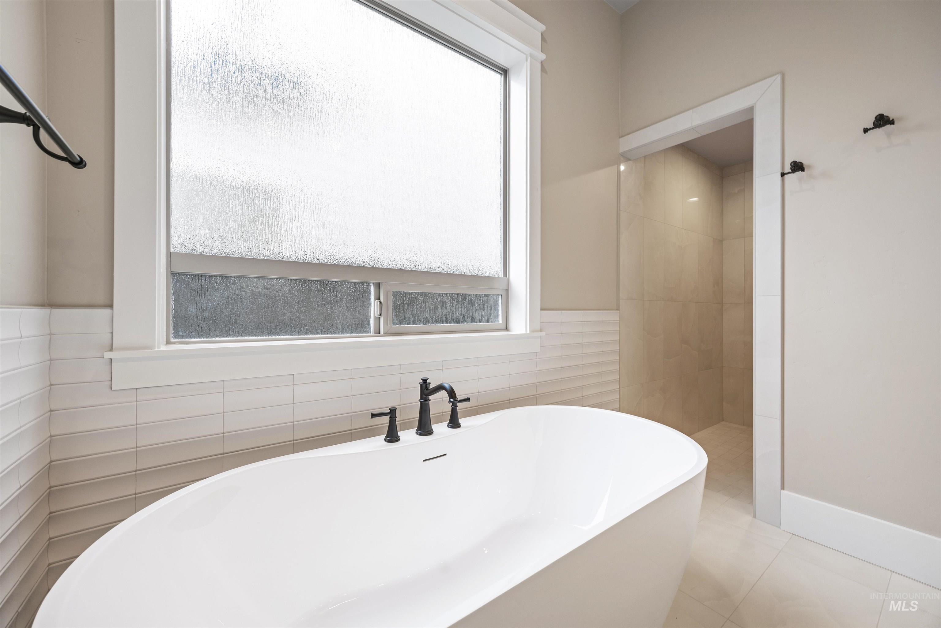 934 East Escalation Street Meridian, ID 83642 - Photo 14 of 50 Bathroom featuring a freestanding bath, tile walls, light tile patterned floors, and a tile shower