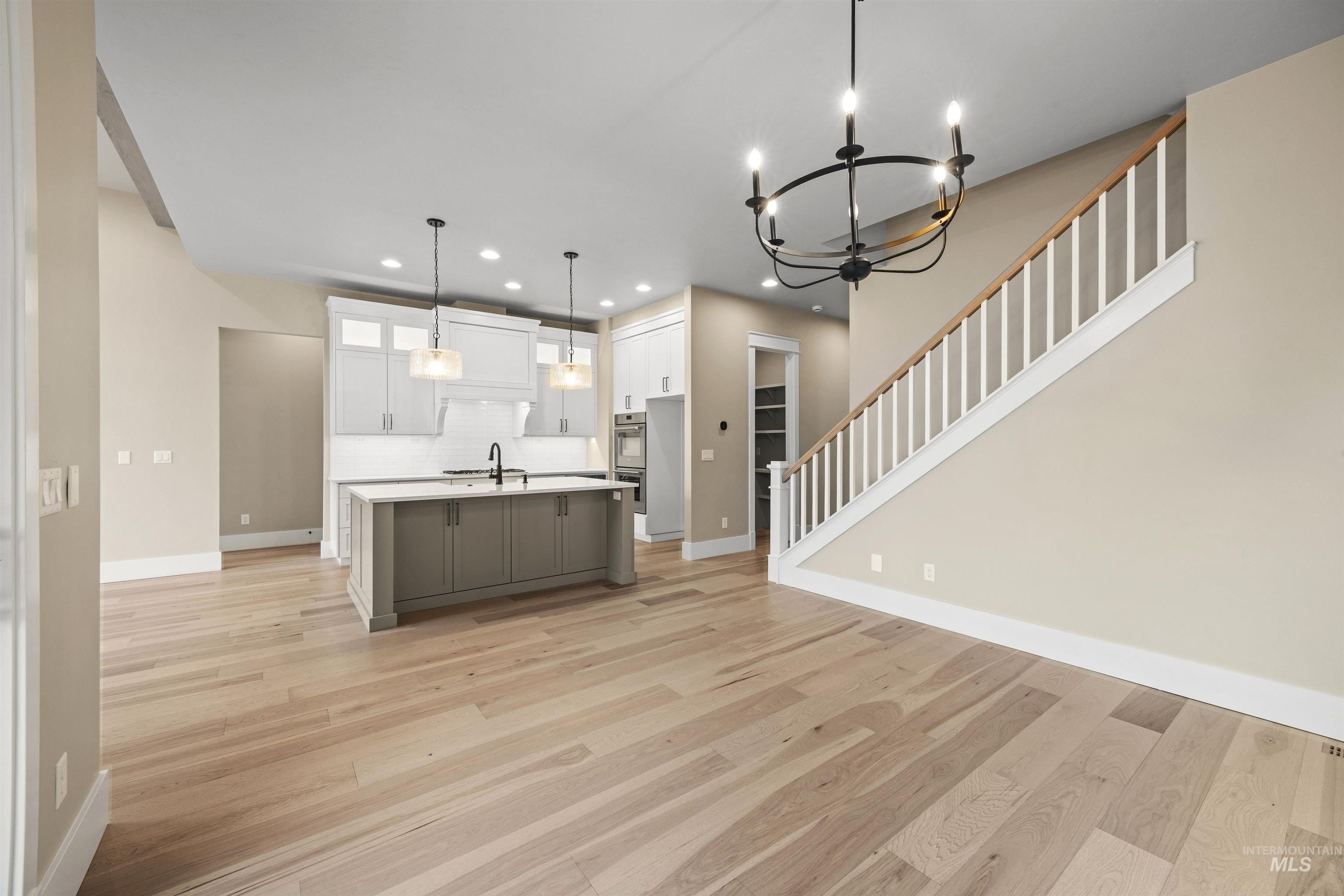 934 East Escalation Street Meridian, ID 83642 - Photo 50 of 50 Two tone kitchen featuring hanging lights, a center island with sink, light wood-type flooring, dual tone cabinets, and open floor plan