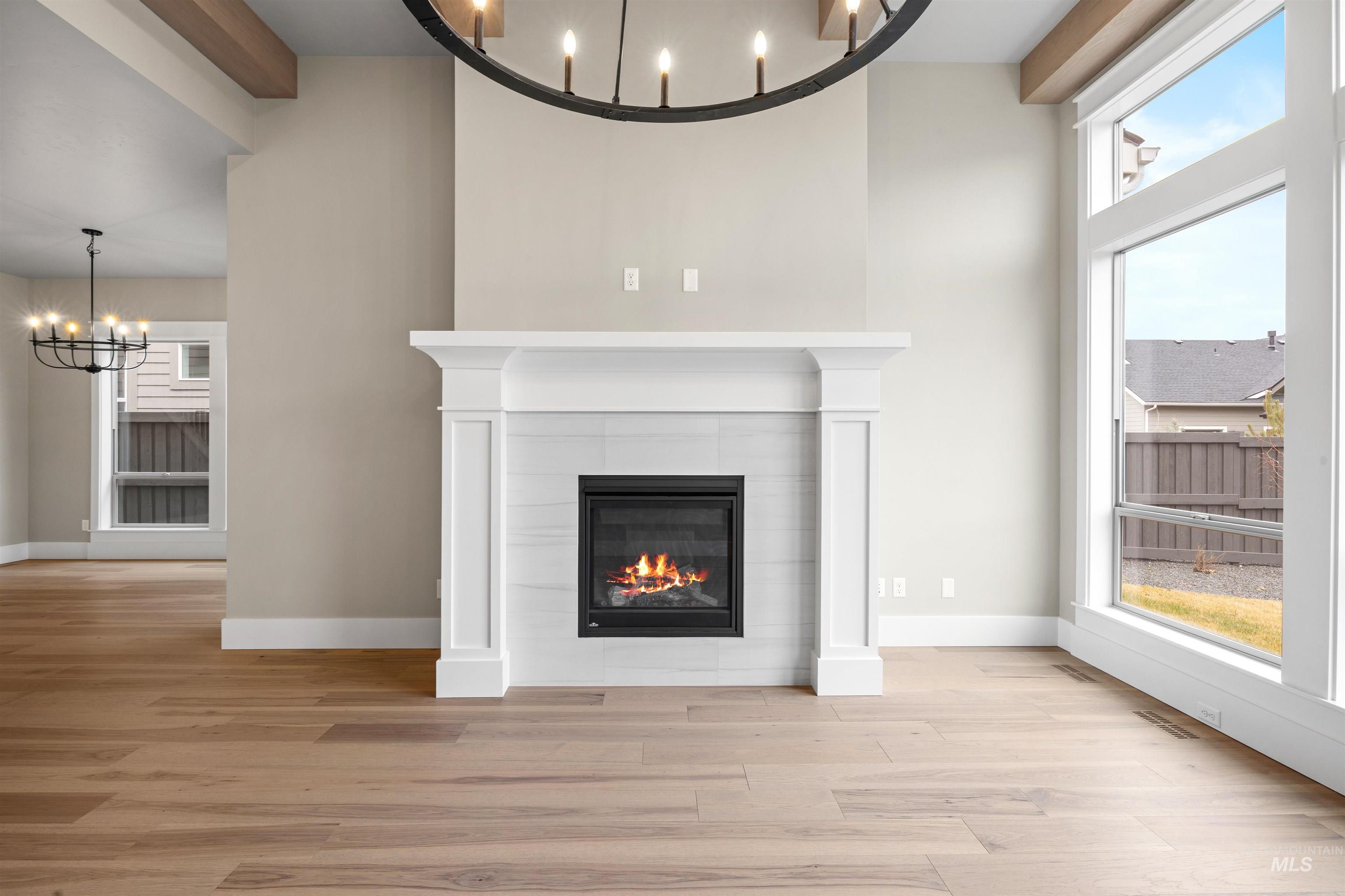 934 East Escalation Street Meridian, ID 83642 - Photo 23 of 50 Unfurnished living room with hanging lights, light wood finished floors, a tiled fireplace, and a high ceiling