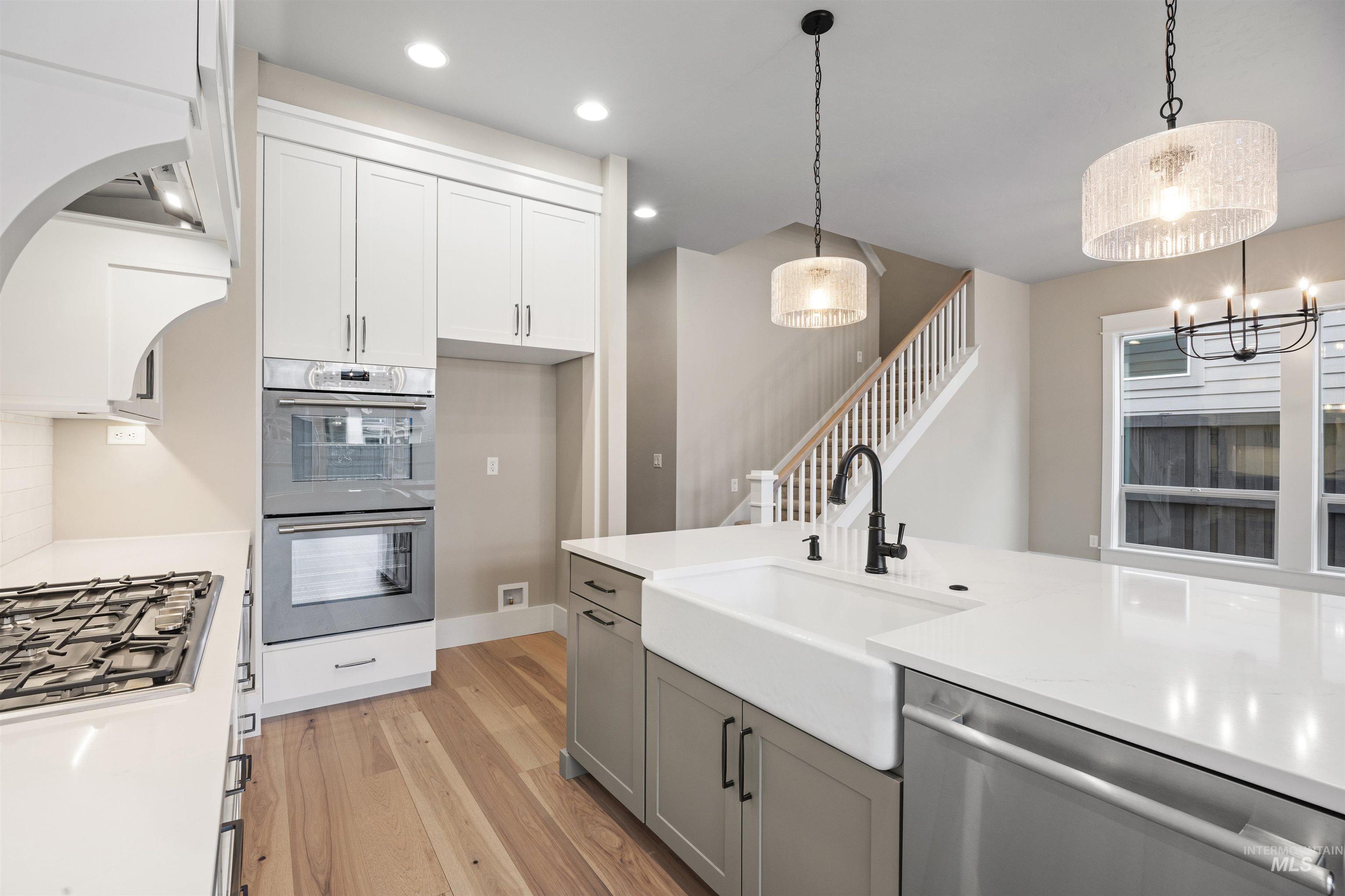 934 East Escalation Street Meridian, ID 83642 - Photo 26 of 50 Kitchen with two tone cabinets, stainless steel appliances, light wood finished floors, light stone counters, and decorative backsplash