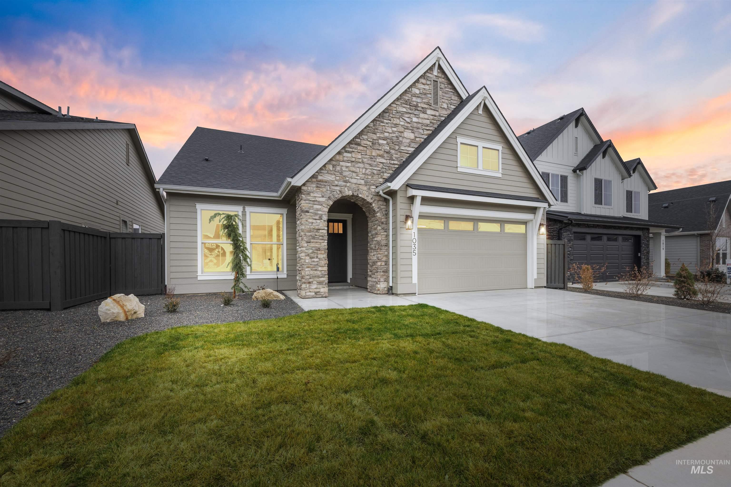 934 East Escalation Street Meridian, ID 83642 - Photo 3 of 50 View of front of property featuring stone siding, driveway, board and batten siding, a garage, and a shingled roof