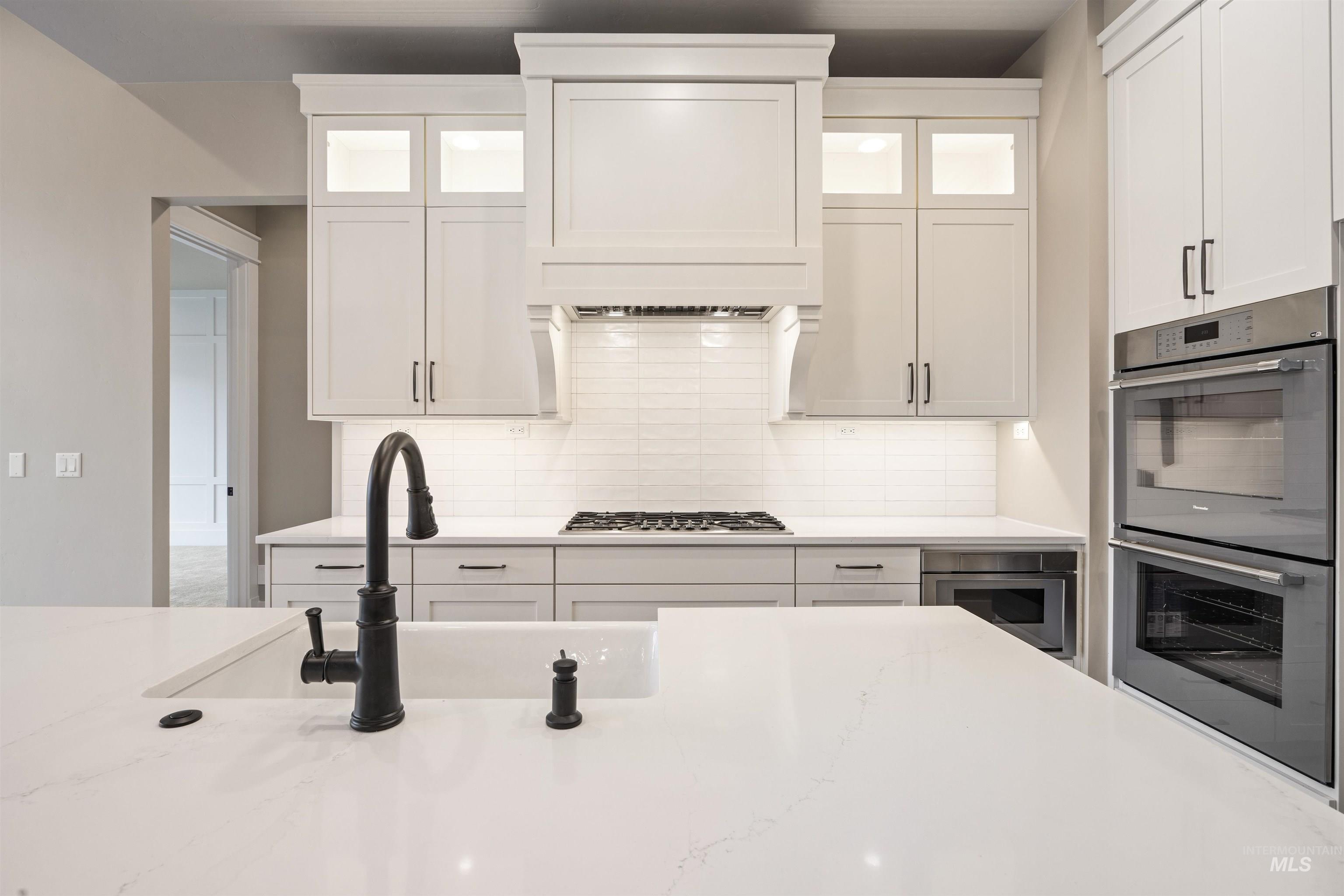 934 East Escalation Street Meridian, ID 83642 - Photo 30 of 50 Kitchen with glass insert cabinets, stainless steel appliances, white cabinetry, and decorative backsplash