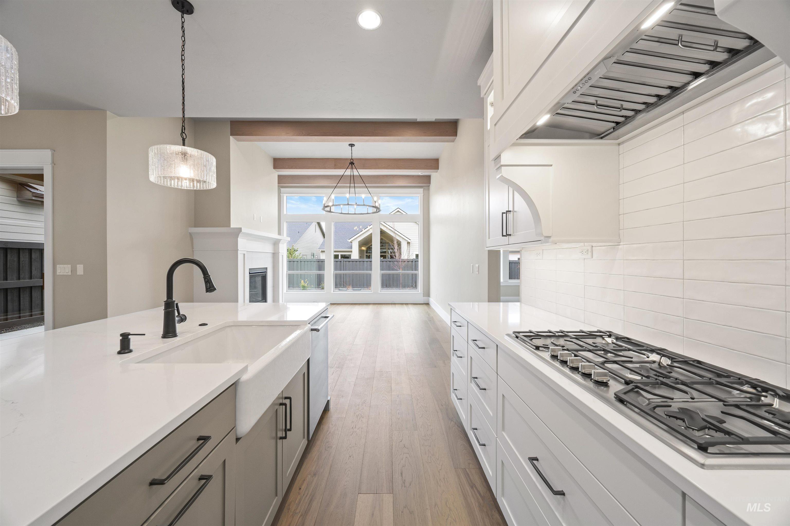 934 East Escalation Street Meridian, ID 83642 - Photo 33 of 50 Kitchen featuring stainless steel appliances, light wood-type flooring, decorative light fixtures, two tone cabinets, and a glass covered fireplace