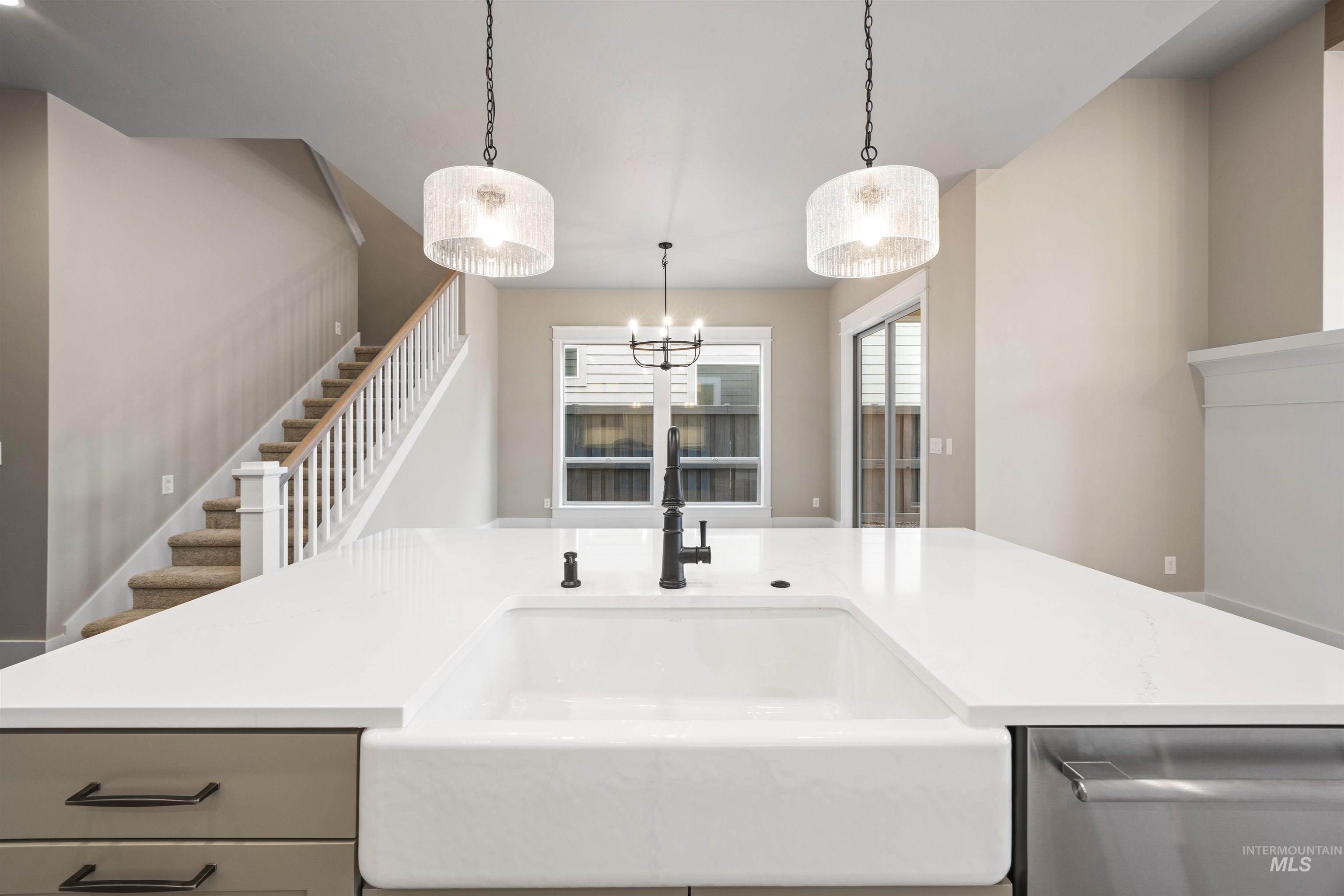 934 East Escalation Street Meridian, ID 83642 - Photo 34 of 50 Kitchen with stainless steel dishwasher, decorative light fixtures, light stone counters, and an island with sink