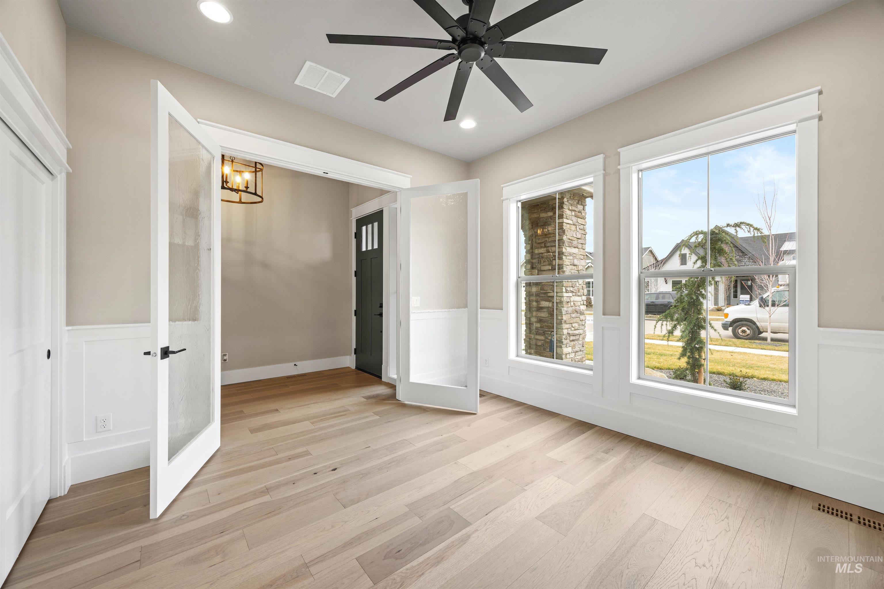 934 East Escalation Street Meridian, ID 83642 - Photo 6 of 50 Unfurnished bedroom featuring wainscoting, light wood finished floors, ceiling fan, a decorative wall, and hanging lights
