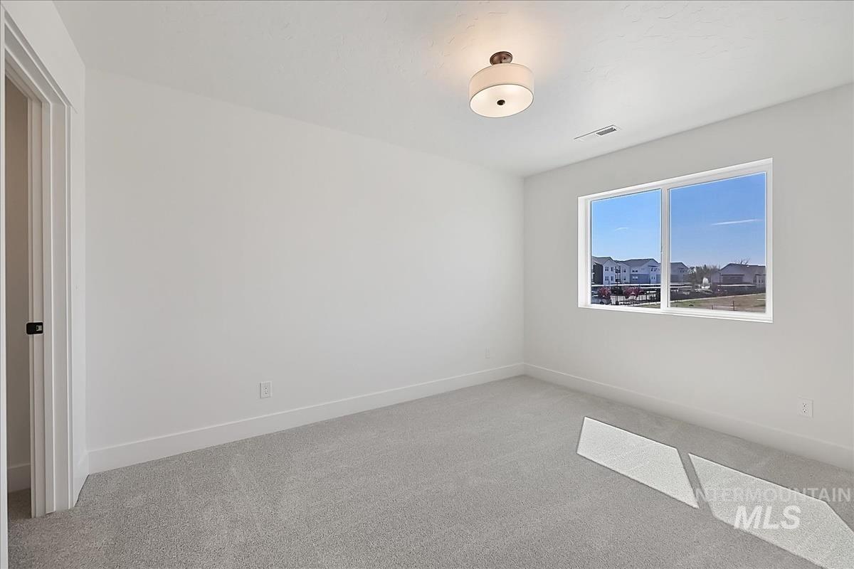 776 South Calhoun Lane Star, ID 83669 - Photo 32 of 49 Bright interior room featuring a large window, light gray carpet, white walls, and a contemporary flush-mount ceiling light