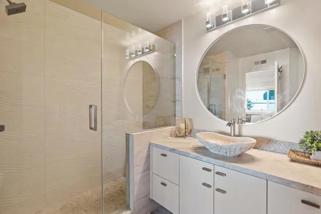 a bathroom with a granite countertop sink a mirror and shower