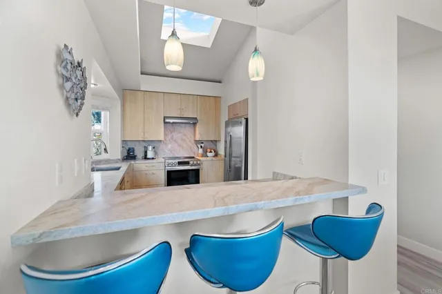 a kitchen with stainless steel appliances granite countertop a sink a stove and chairs