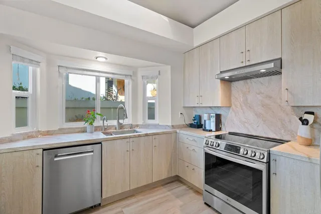 a kitchen with granite countertop stainless steel appliances a sink cabinets and a window