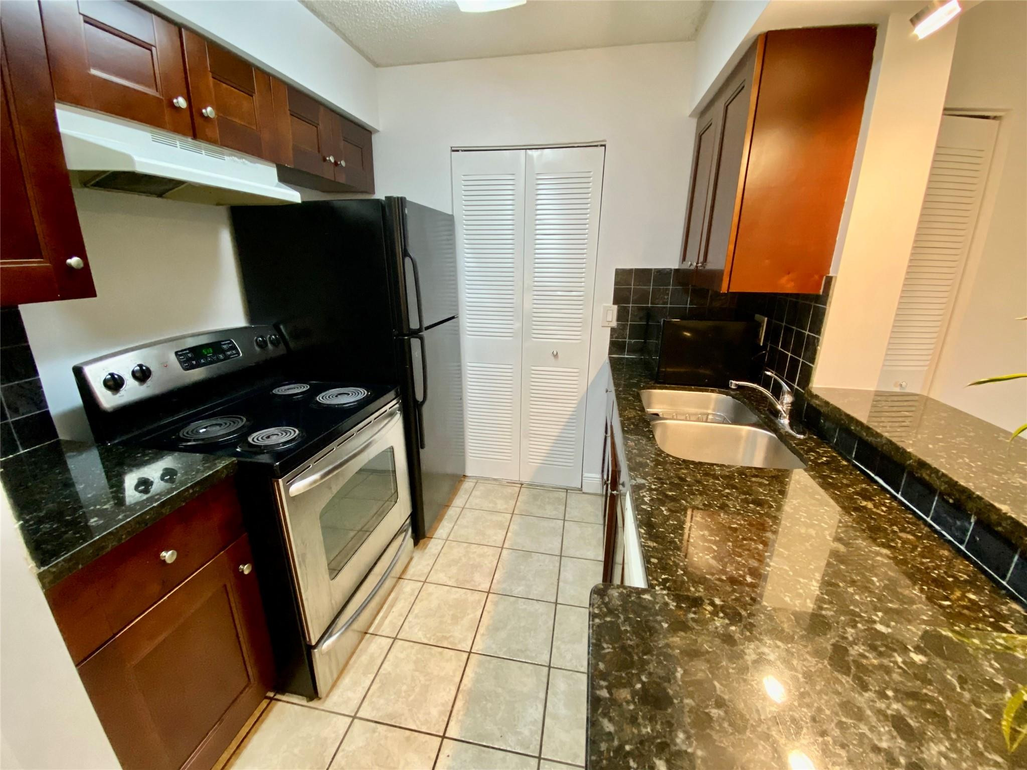 1247 Southwest 46th Avenue, Unit 1301 Pompano Beach, FL 33069 - Photo 7 of 22 a kitchen with a sink a stove cabinetry and a refrigerator