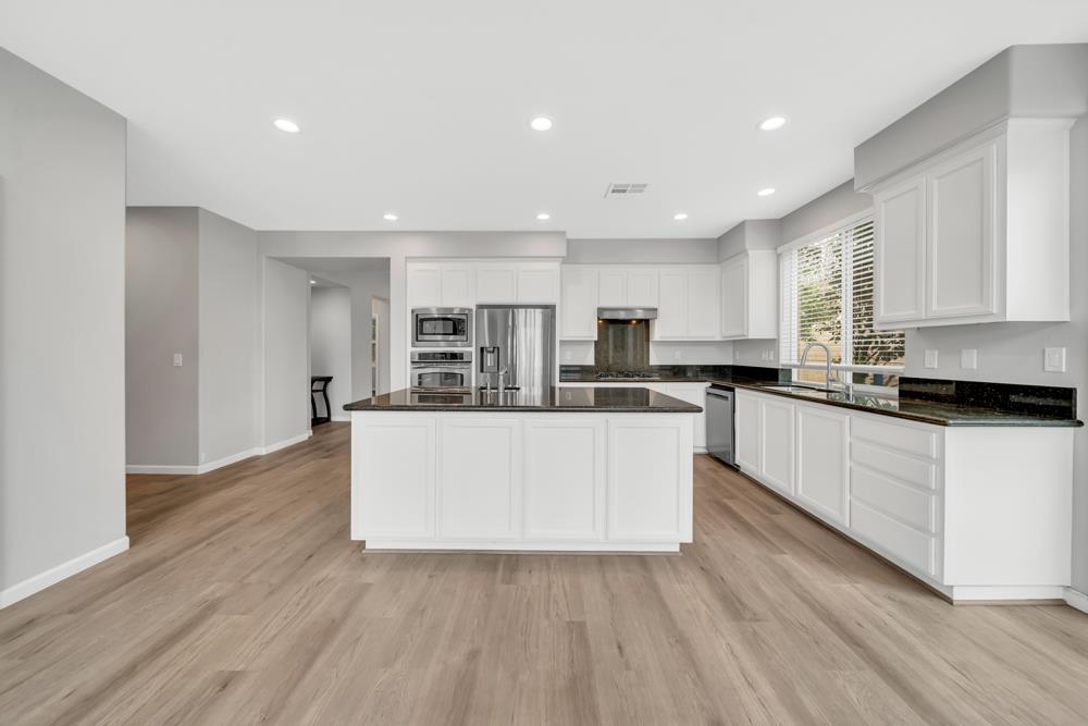 20300 Panoz Road Patterson, CA 95363 - Photo 12 of 61 a large white kitchen with kitchen island sink refrigerator and white cabinets