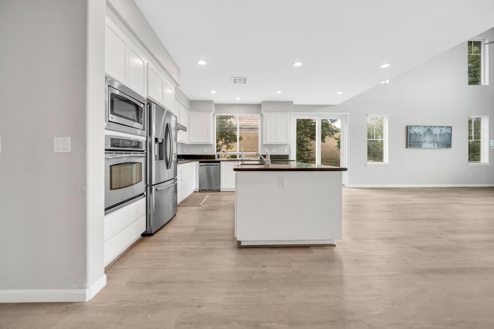 20300 Panoz Road Patterson, CA 95363 - Photo 7 of 61 a kitchen with stainless steel appliances granite countertop a refrigerator oven a sink dishwasher and white cabinets with wooden floor