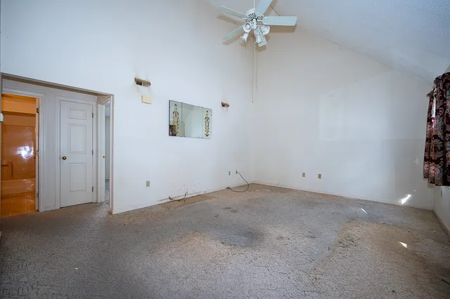 an empty room with a chandelier fan and windows