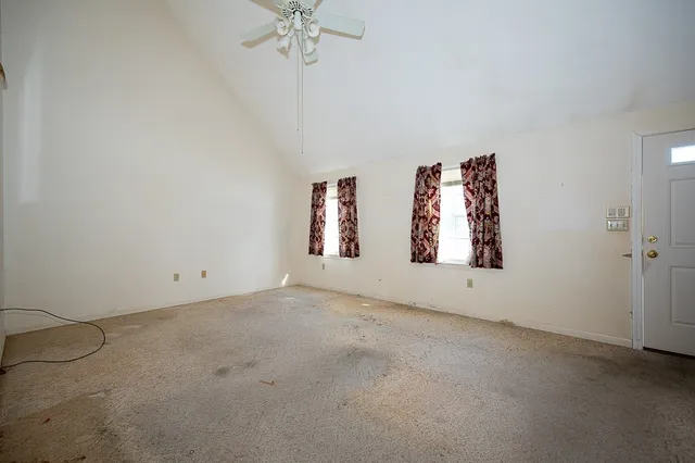 an empty room with windows and chandelier fan