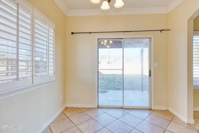 an empty room with chandelier fan and windows
