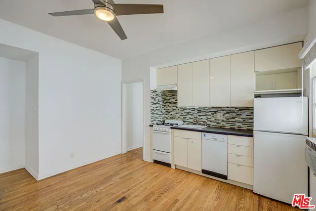 a view of empty room with wooden floor and ceiling fan