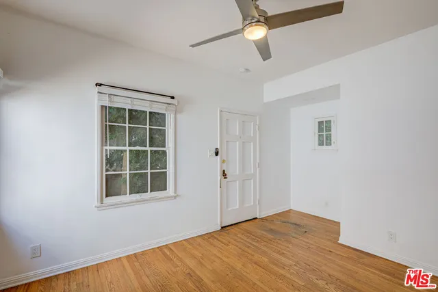 a view of empty room with wooden floor and fan