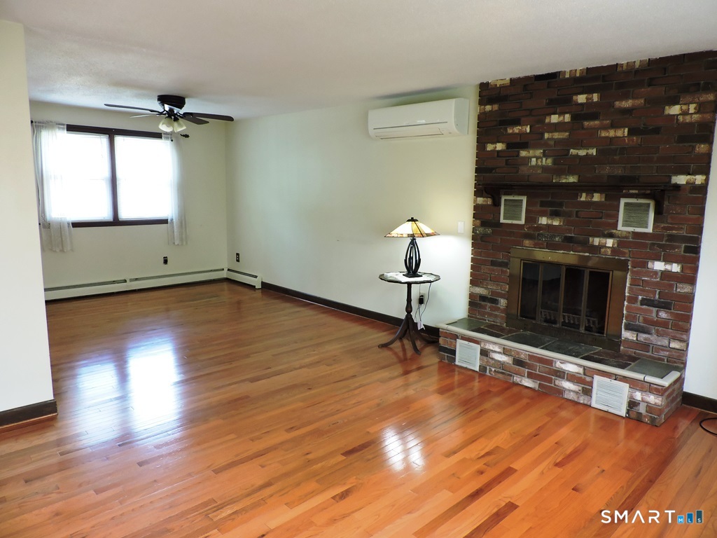 269 Griffin Road South Windsor, CT 06074 - Photo 12 of 36 an empty room with wooden floor fireplace and windows
