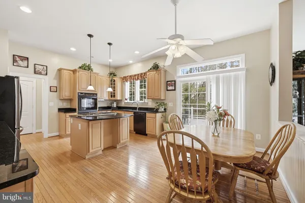 a kitchen with stainless steel appliances granite countertop a refrigerator a stove top oven a sink and dishwasher with wooden floor