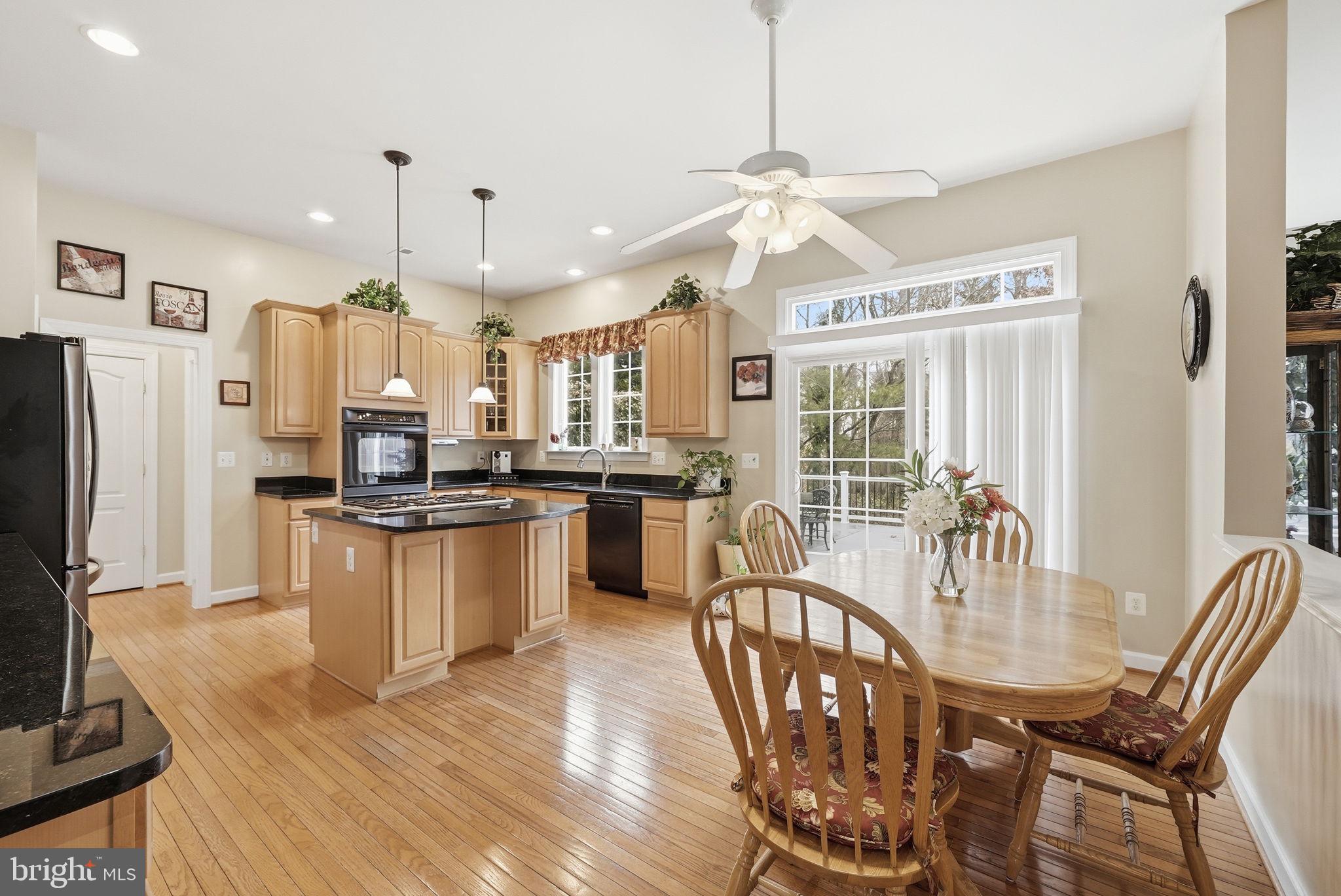 7820 Rose Garden Lane Springfield, VA 22153 - Photo 19 of 65 a kitchen with stainless steel appliances kitchen island granite countertop a refrigerator a stove a microwave oven a dining table and chairs with wooden floor