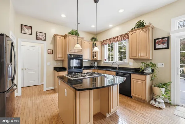 a kitchen with stainless steel appliances granite countertop a stove refrigerator a dining table and chairs with wooden floor