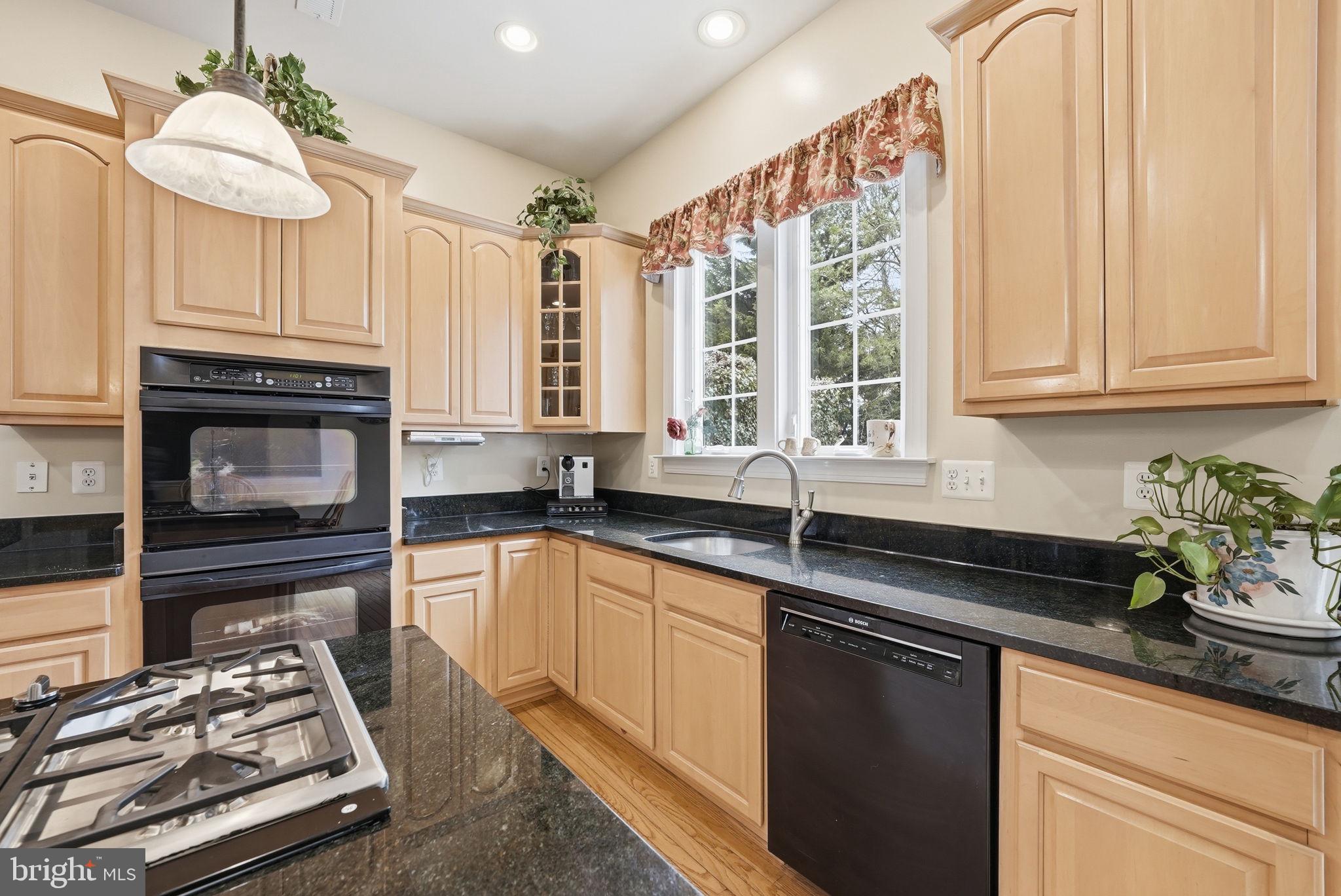 7820 Rose Garden Lane Springfield, VA 22153 - Photo 23 of 65 a kitchen with granite countertop a stove a sink and dishwasher wooden cabinets with wooden floor