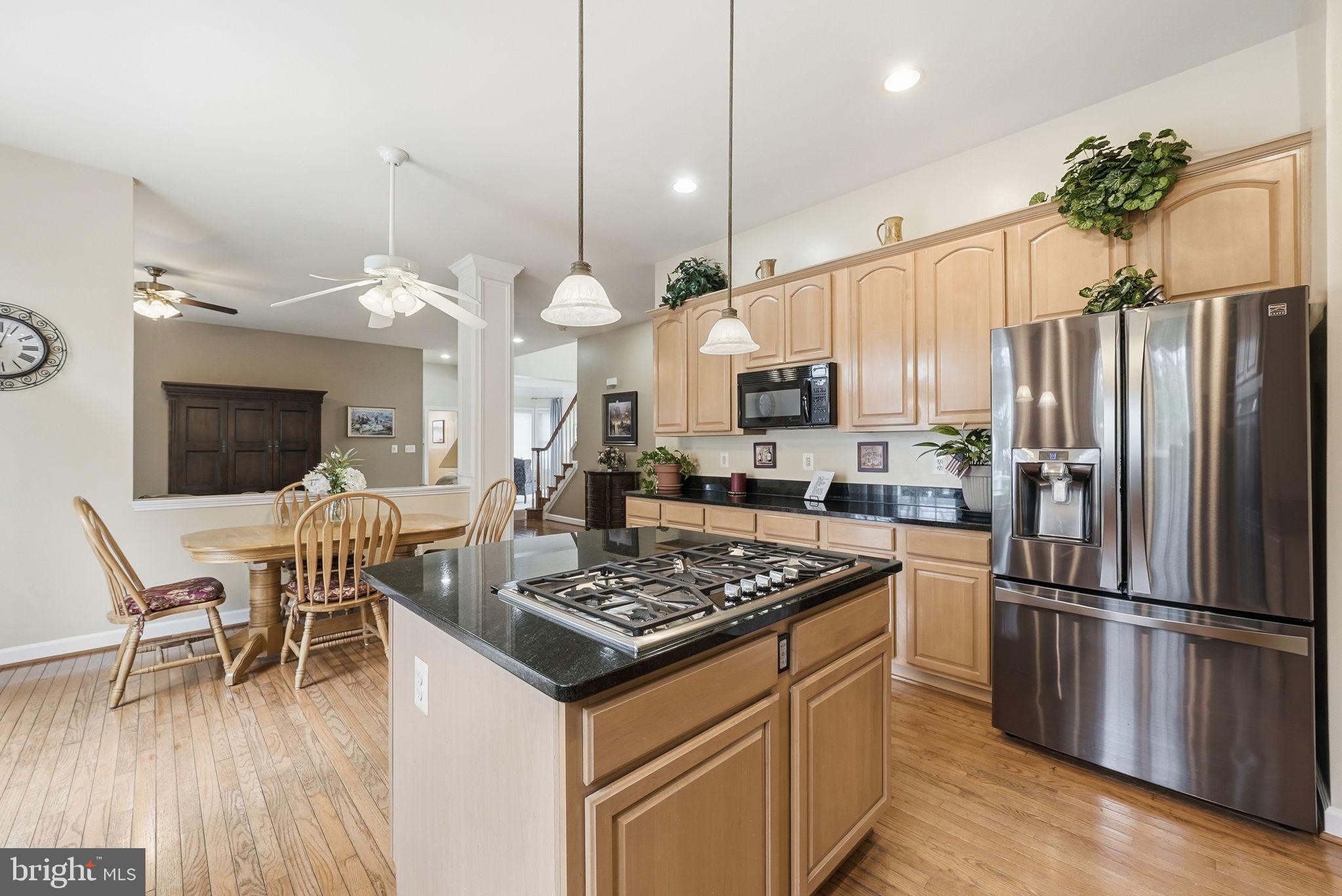 7820 Rose Garden Lane Springfield, VA 22153 - Photo 24 of 65 a kitchen with stainless steel appliances granite countertop a stove refrigerator a dining table and chairs with wooden floor