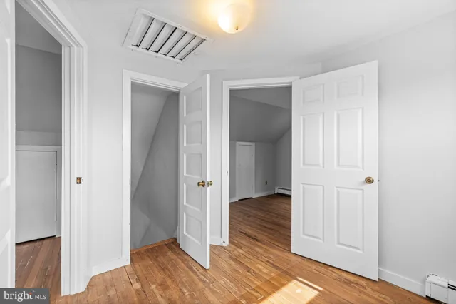 a view of a hallway with wooden floor and closet area