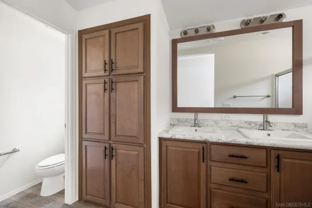 a bathroom with a granite countertop sink vanity mirror and toilet