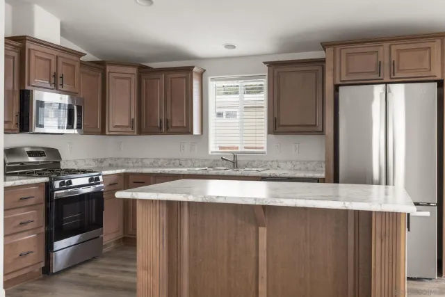 a kitchen with granite countertop a refrigerator stove and sink