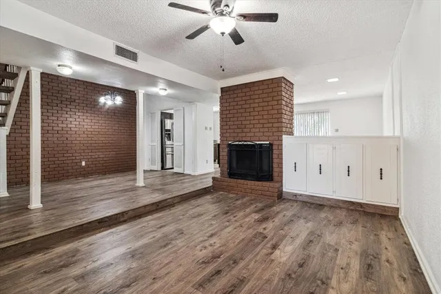 a view of an empty room with wooden floor and a fireplace