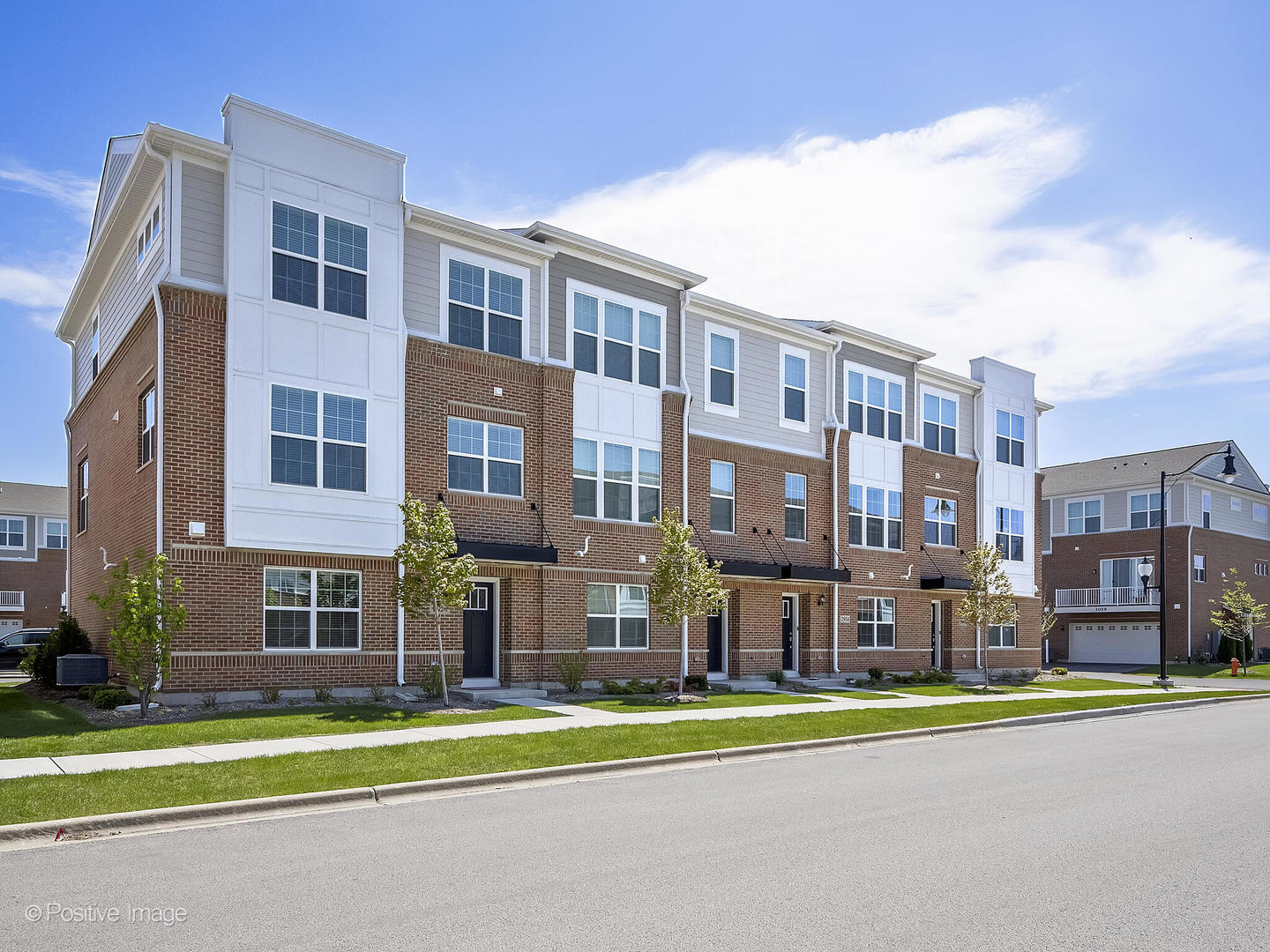 a front view of a residential apartment building with a yard and trees