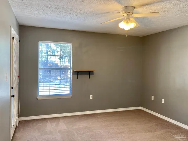 an empty room with windows and fan