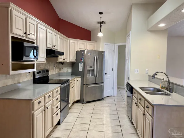 a kitchen with stainless steel appliances granite countertop a sink a stove a refrigerator cabinets a sink and a stove