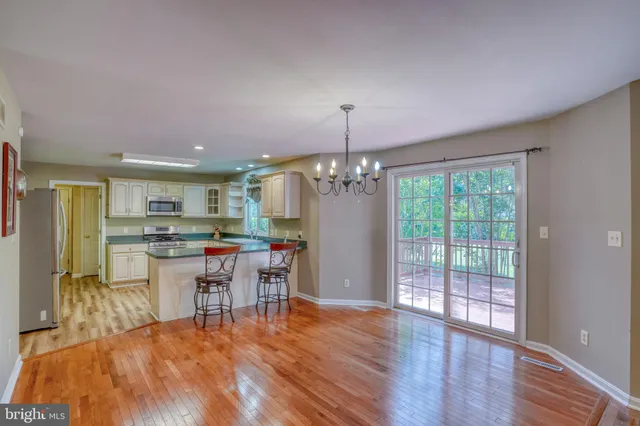a kitchen with stainless steel appliances granite countertop a refrigerator dining table and chairs