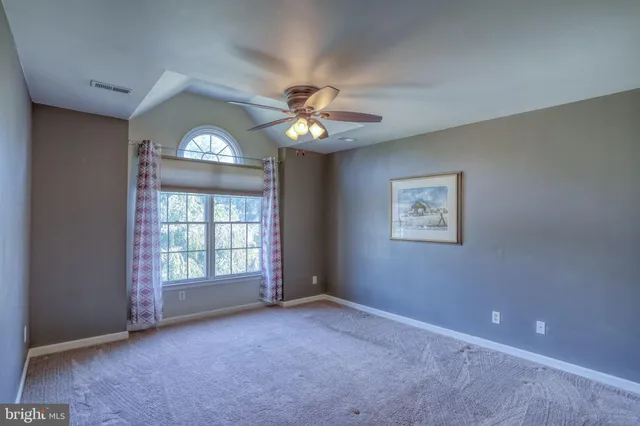 an empty room with a window and a fan