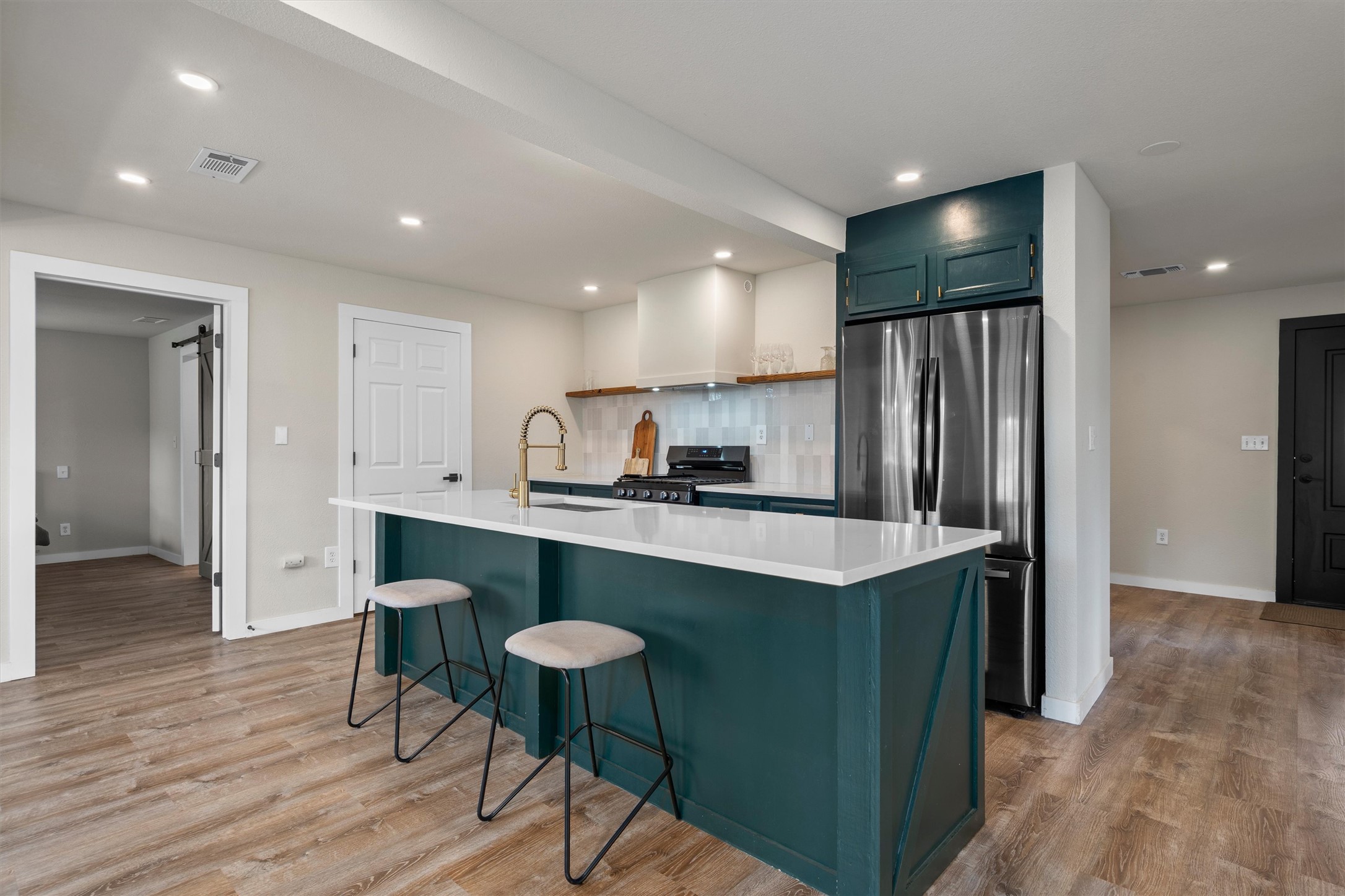 836 Cottle Town Road Smithville, TX 78957 - Photo 16 of 40 Kitchen featuring freestanding refrigerator, black gas stove, a kitchen island with sink, light wood-style floors, and a kitchen breakfast bar