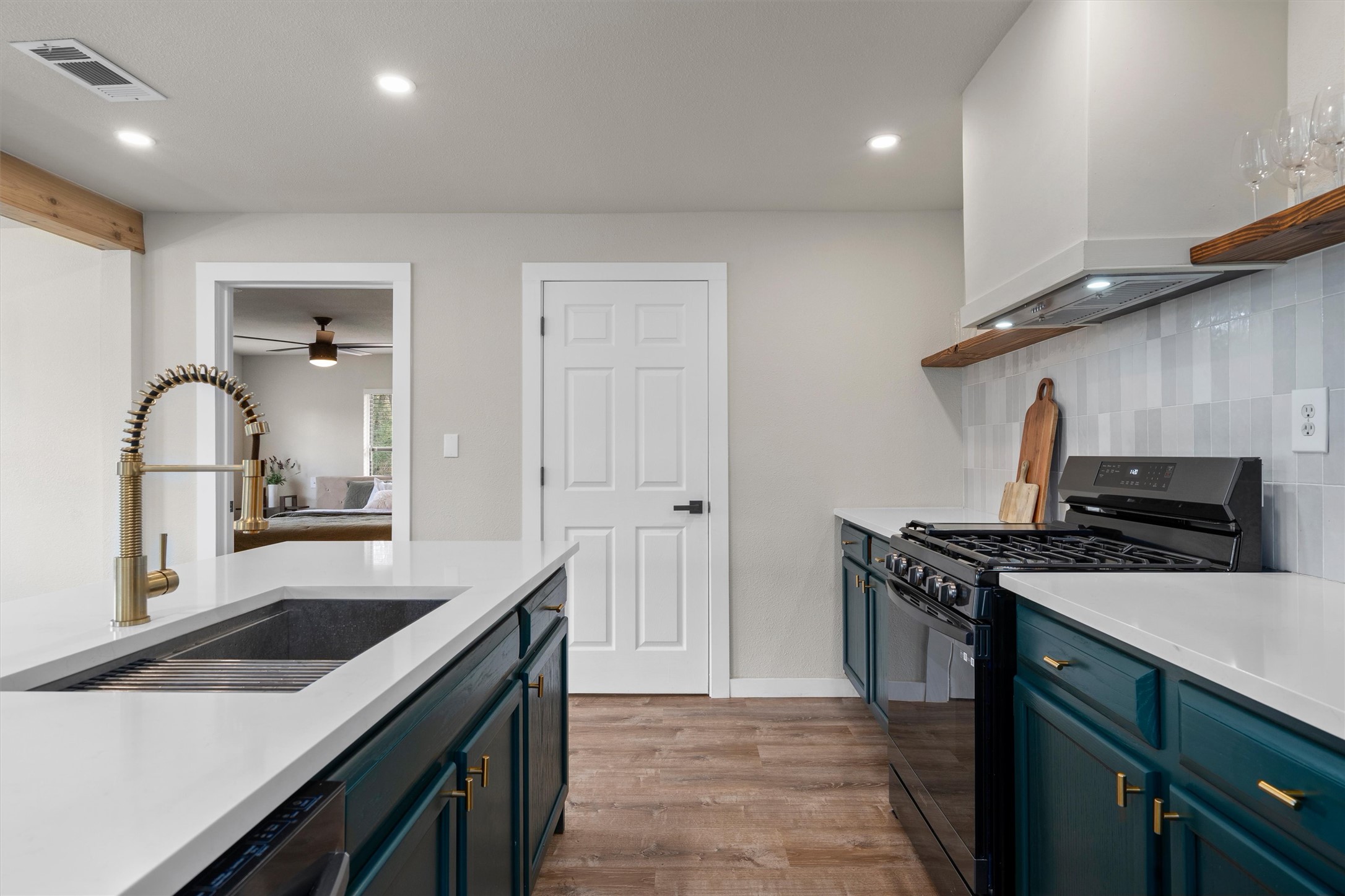836 Cottle Town Road Smithville, TX 78957 - Photo 17 of 40 Kitchen featuring black gas range, light wood-style flooring, tasteful backsplash, recessed lighting, and light stone counters