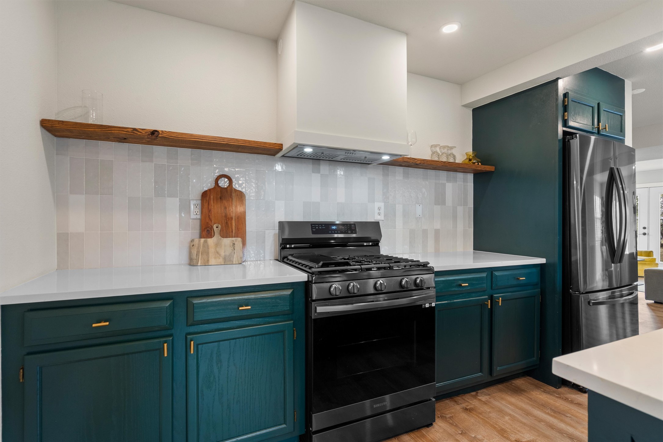 836 Cottle Town Road Smithville, TX 78957 - Photo 18 of 40 Kitchen featuring open shelves, stainless steel appliances, light wood finished floors, tasteful backsplash, and light stone counters