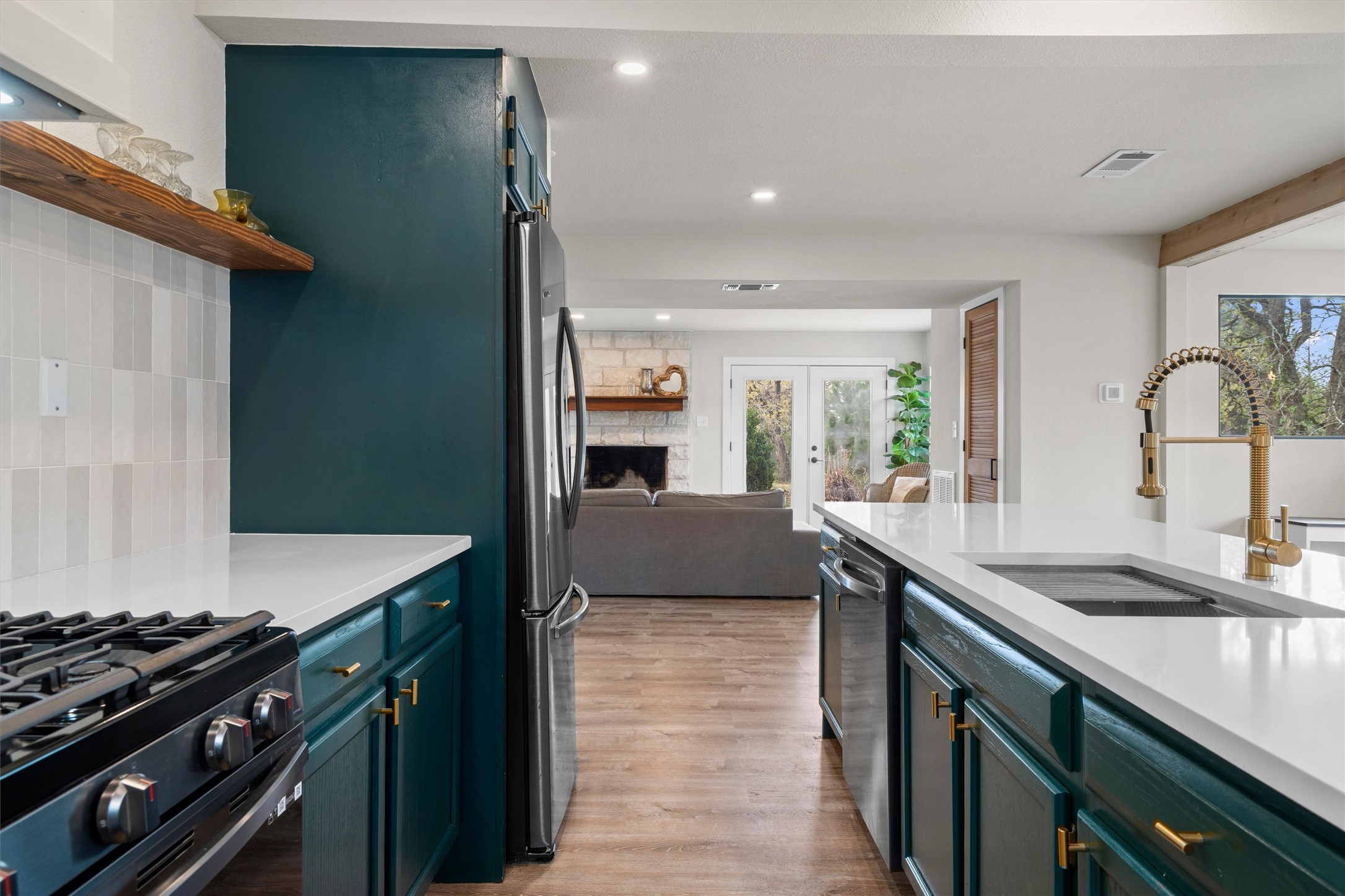 836 Cottle Town Road Smithville, TX 78957 - Photo 39 of 40 Kitchen featuring a stone fireplace, light wood-style floors, stainless steel appliances, open floor plan, and open shelves