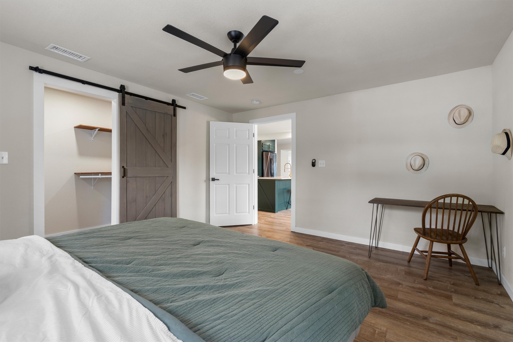 836 Cottle Town Road Smithville, TX 78957 - Photo 19 of 40 Bedroom with a barn door, wood finished floors, a ceiling fan, a walk in closet, and freestanding refrigerator