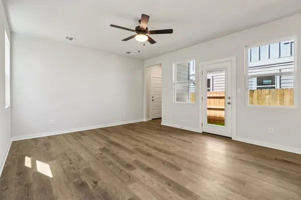 an empty room with wooden floor and windows
