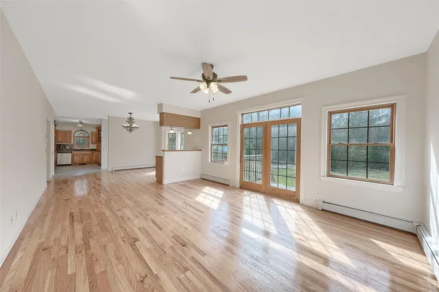 a view of an empty room with a window and wooden floor