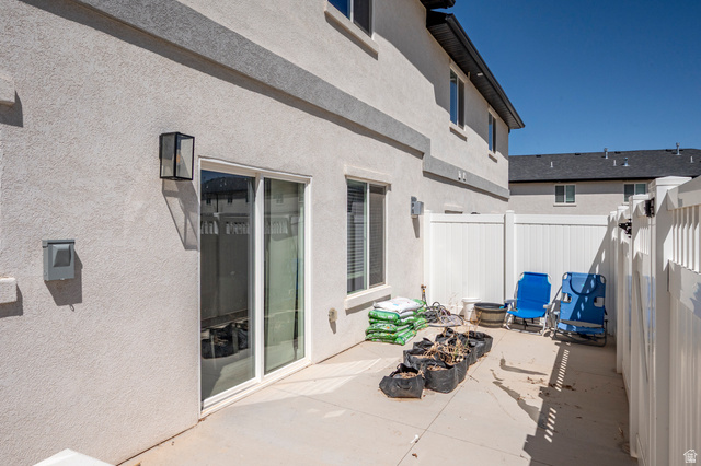 668 East Fiddlers Canyon Road, Unit 6 Cedar City, UT 84721 - Photo 28 of 36 Rear patio area featuring a sliding glass door, stucco exterior, and a privacy fence