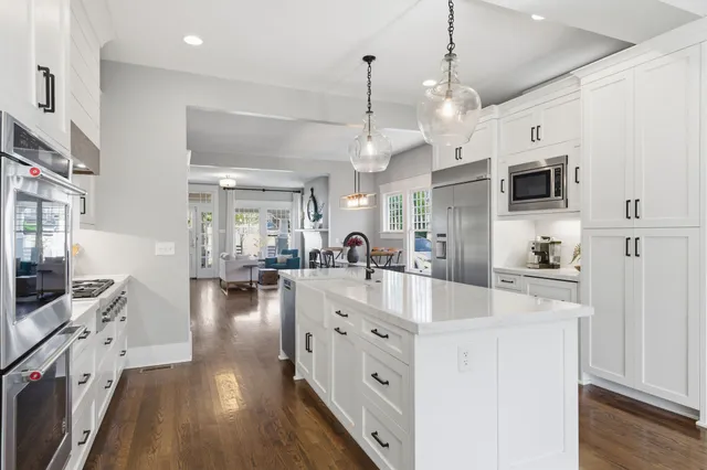 a large white kitchen with lots of counter space a sink and appliances
