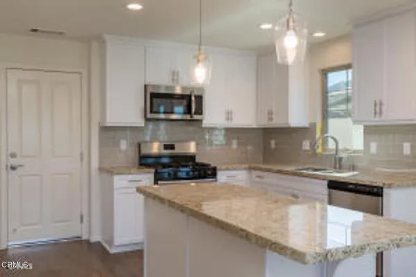 a kitchen with stainless steel appliances granite countertop a sink a stove and a granite counter top